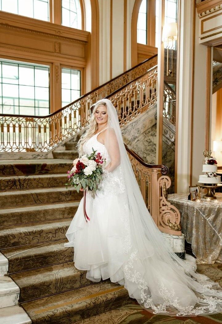 bride standing on stairs  in flowing ballgown 