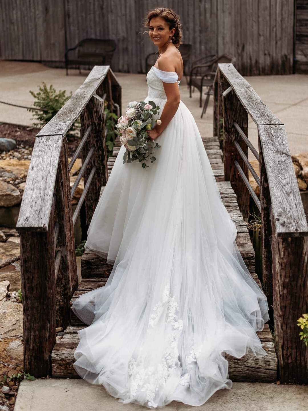 bride in ballgown standing on bridge